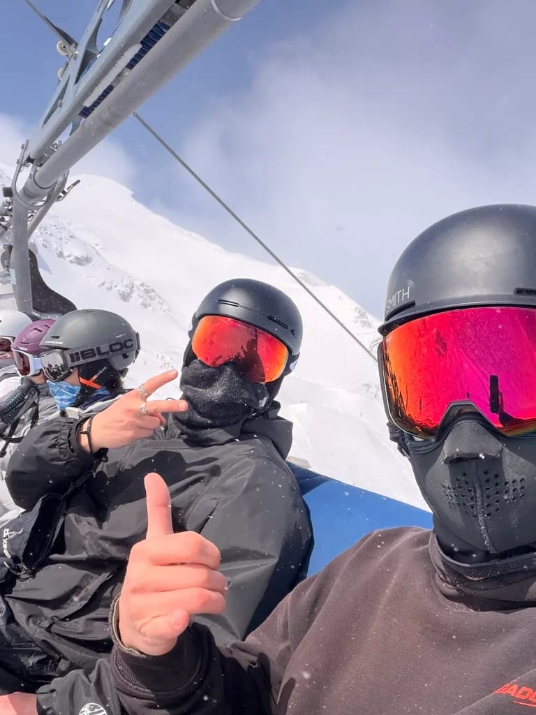Skiers riding a chairlift surrounded by snowy mountains.